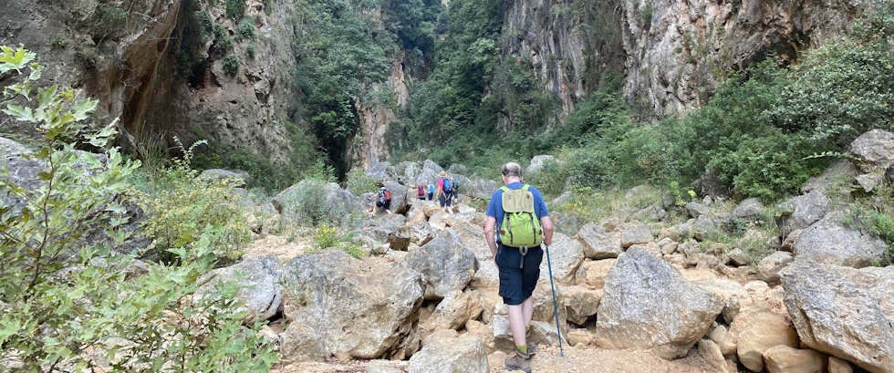 wandelaars met rugzak lopend door een vallei met rotsblokken en begroeiing in Albanië