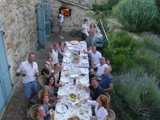 mensen eten aan een lange tafel buiten in Italie