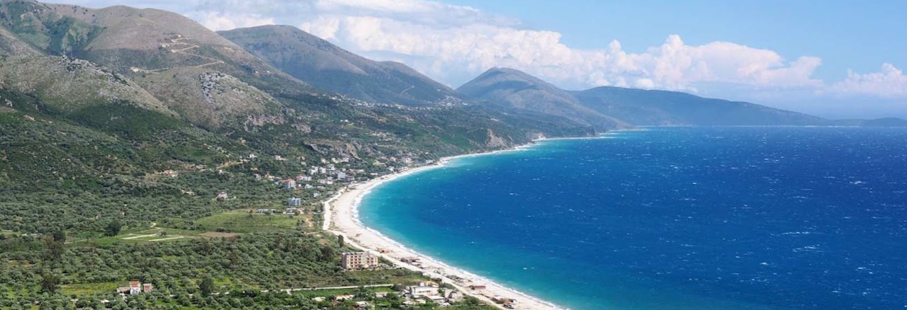 Individuele wandelreis Zuid Albanië coastal trail, 8 dgn Blauwe baai omringd met bergen op de achtergrond in zuid Albanië