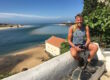 Man zittend op muurtje met zee op de achtergrond op de rota vicentina in Portugal.