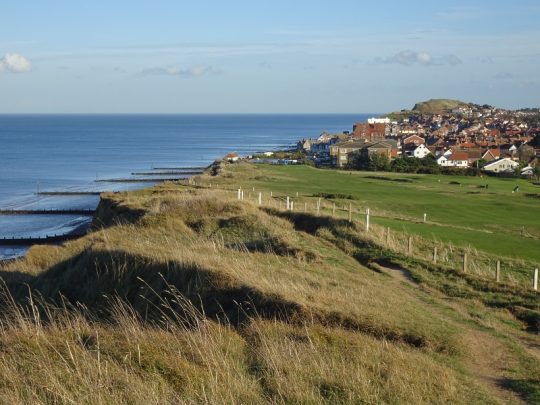dorp en grasvlakte aan de kust in Engeland