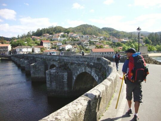 wandelaar met rugzak op oude stenen brug onderweg naar Santiago de Compostela.